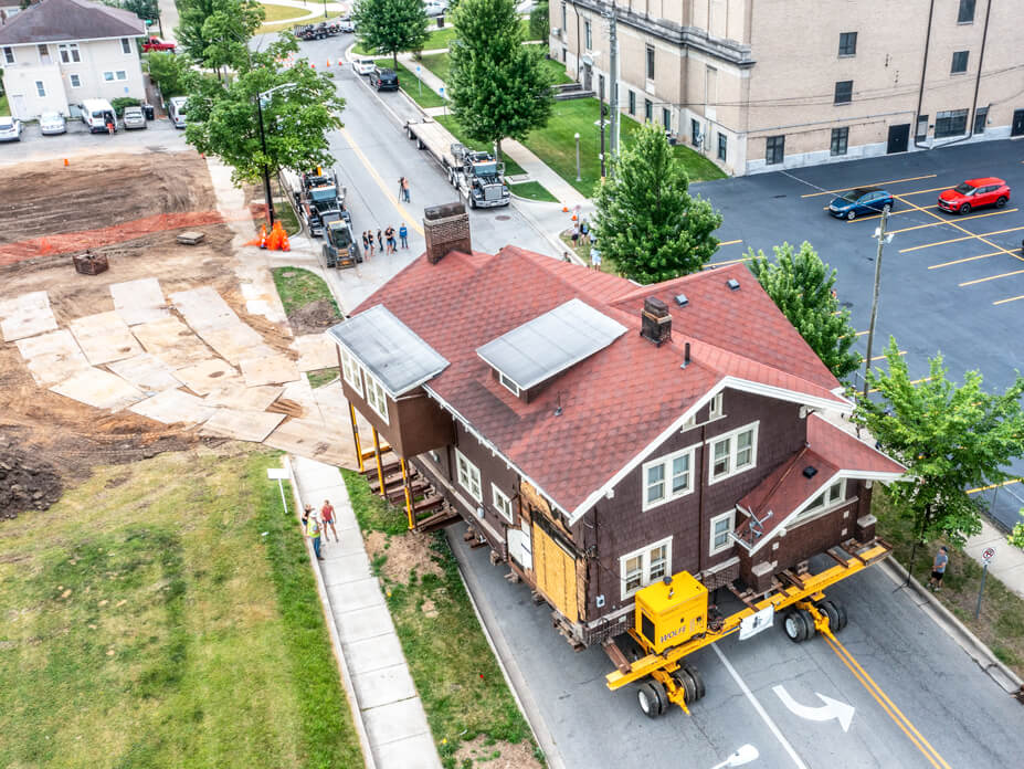 Aerial view of Wolfe moving a brown Craftsman-style house down the street