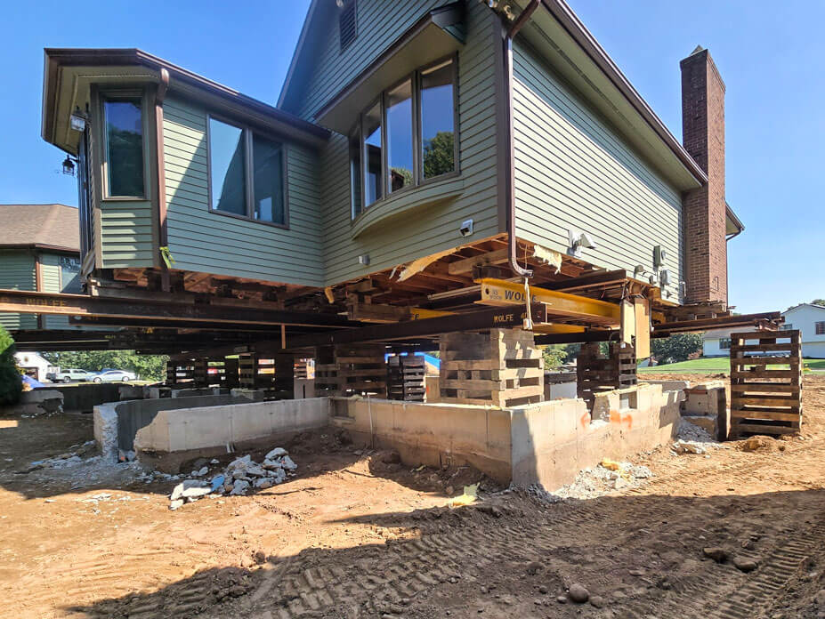 Corner view of house elevated on steel and cribbing for foundation replacement