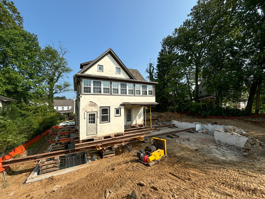 Wolfe slides a two-story house across roll beams to its new foundation