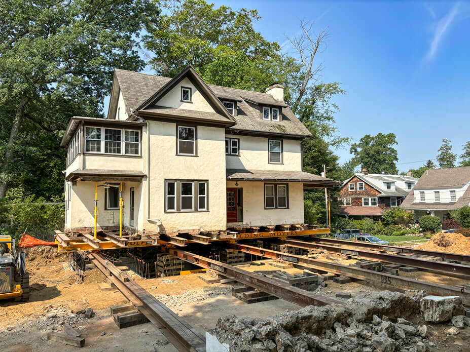 Cream-colored terracotta house sits over its new foundation with roll beams in foreground