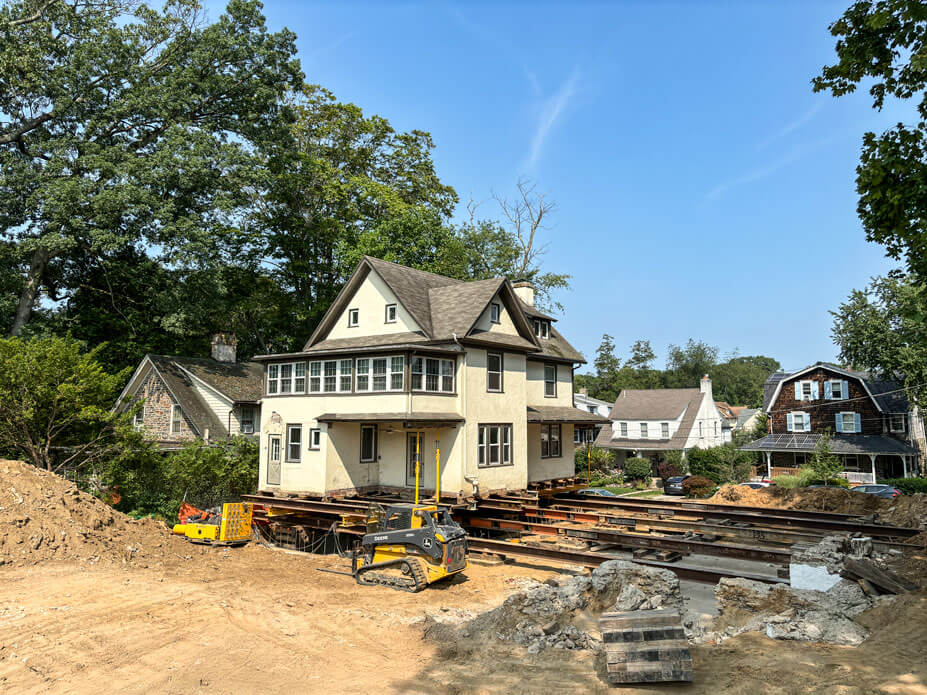 Rollbeams with skidsteer and terracotta house on beams over its new foundation