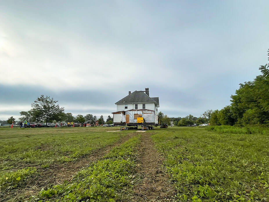 House sits on wheels for relocation with field in foreground