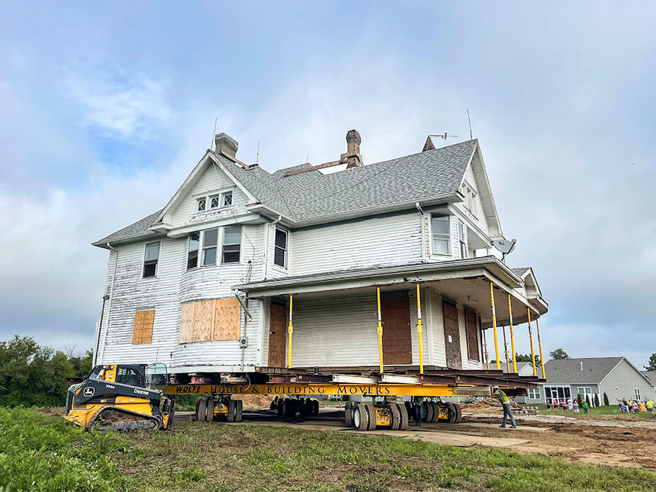 White house on yellow Wolfe House Movers beams and dollies