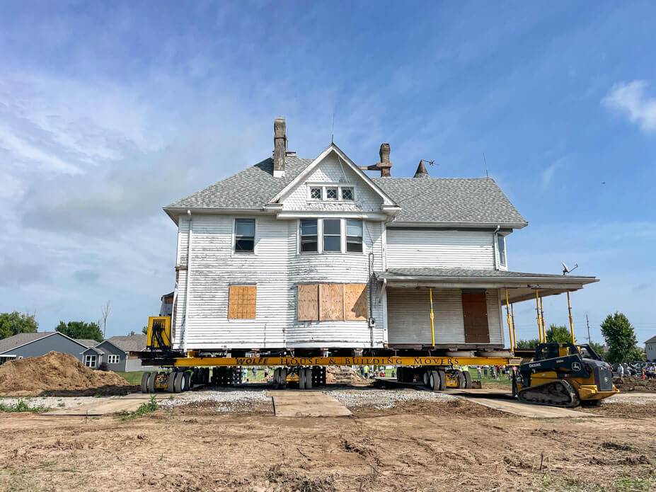 Historic white Plainfield, IN house sits on housemoving dollies over its new foundation