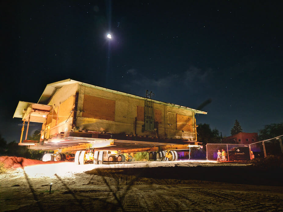 Night sky over single-story house being relocated by Wolfe on housemoving dollies