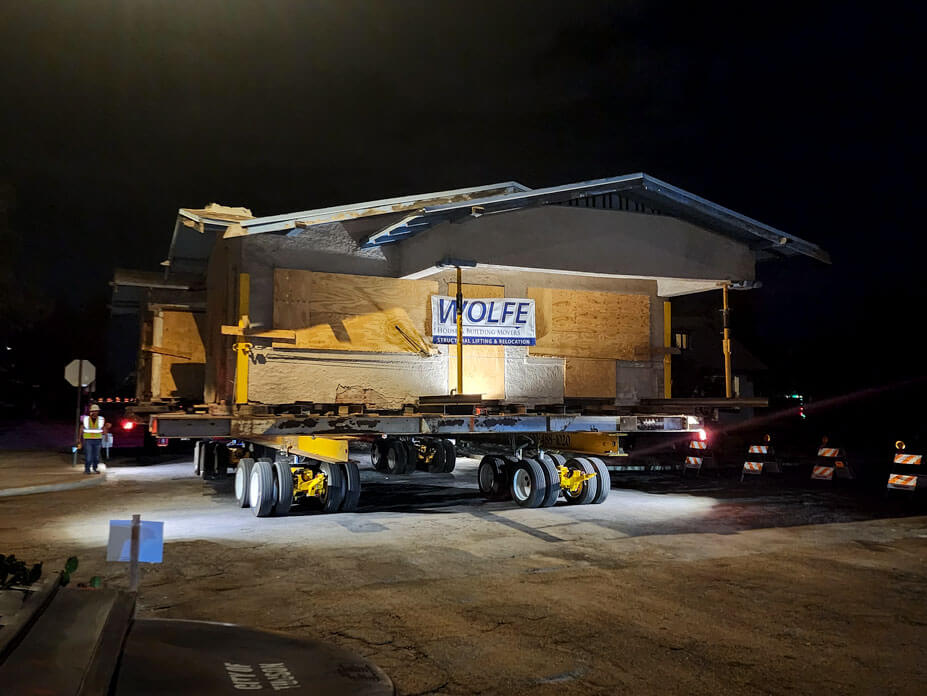 Nightime view of house with Wolfe banner and dollies as it is being relocated