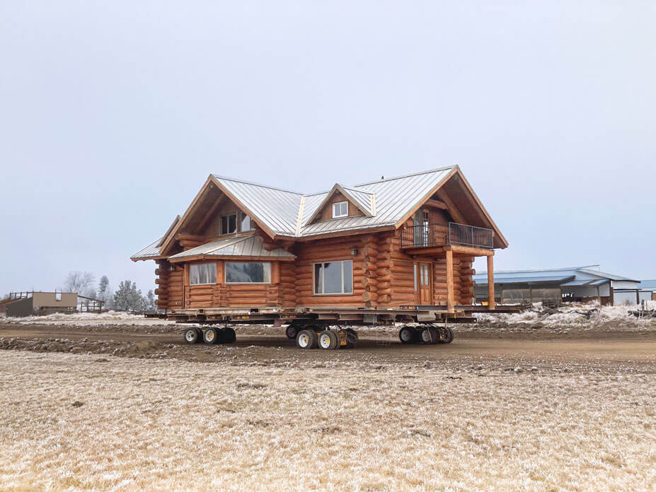 Corner view of two-story log cabin on Wolfe housemoving dollies